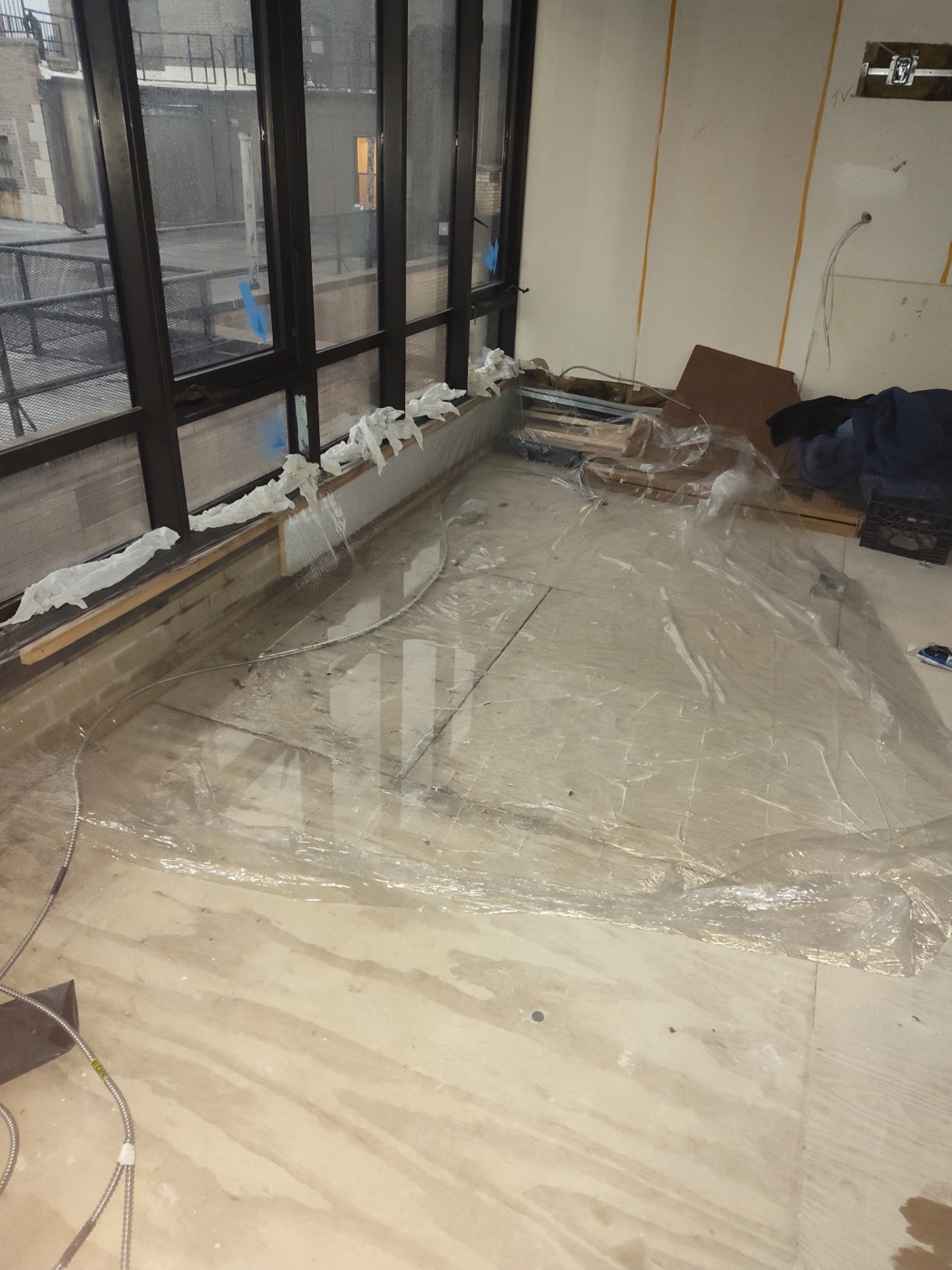 Towels lining every window sill and plastic sheeting across a water-stained floor